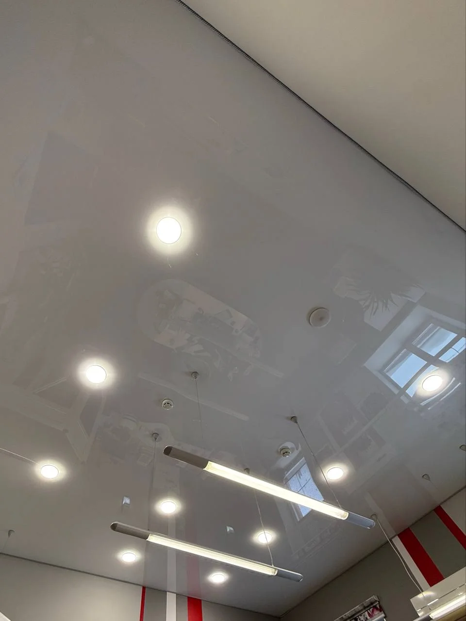 Глянцевый потолок в офис с точечным и подвесным освещением