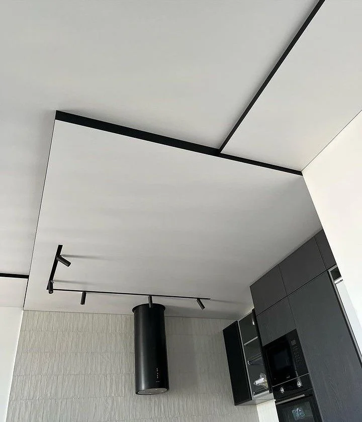 Многоуровневый матовый потолок с черными алюминиевыми профилями и треком на кухню